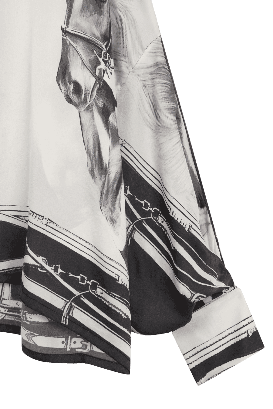 Detalle de la manga de la blusa con estampado ecuestre, donde se aprecia el diseño de caballo en tonos grises y negros, junto a ilustraciones de correas y hebillas, sobre un fondo blanco. El acabado amplio y fluido realza la caída del tejido