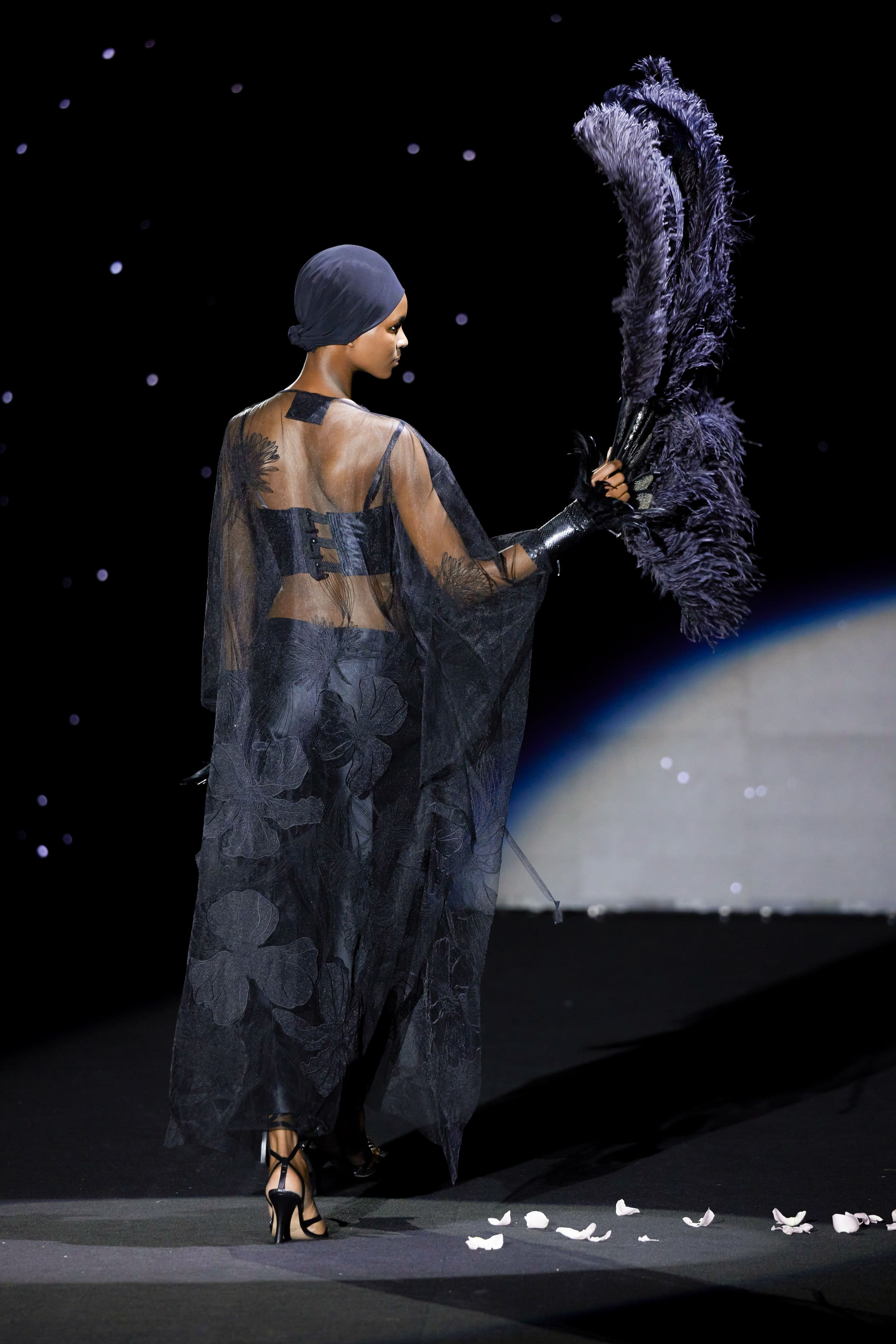 Seen from the back, this silhouette reaffirms its ritual and enveloping character.