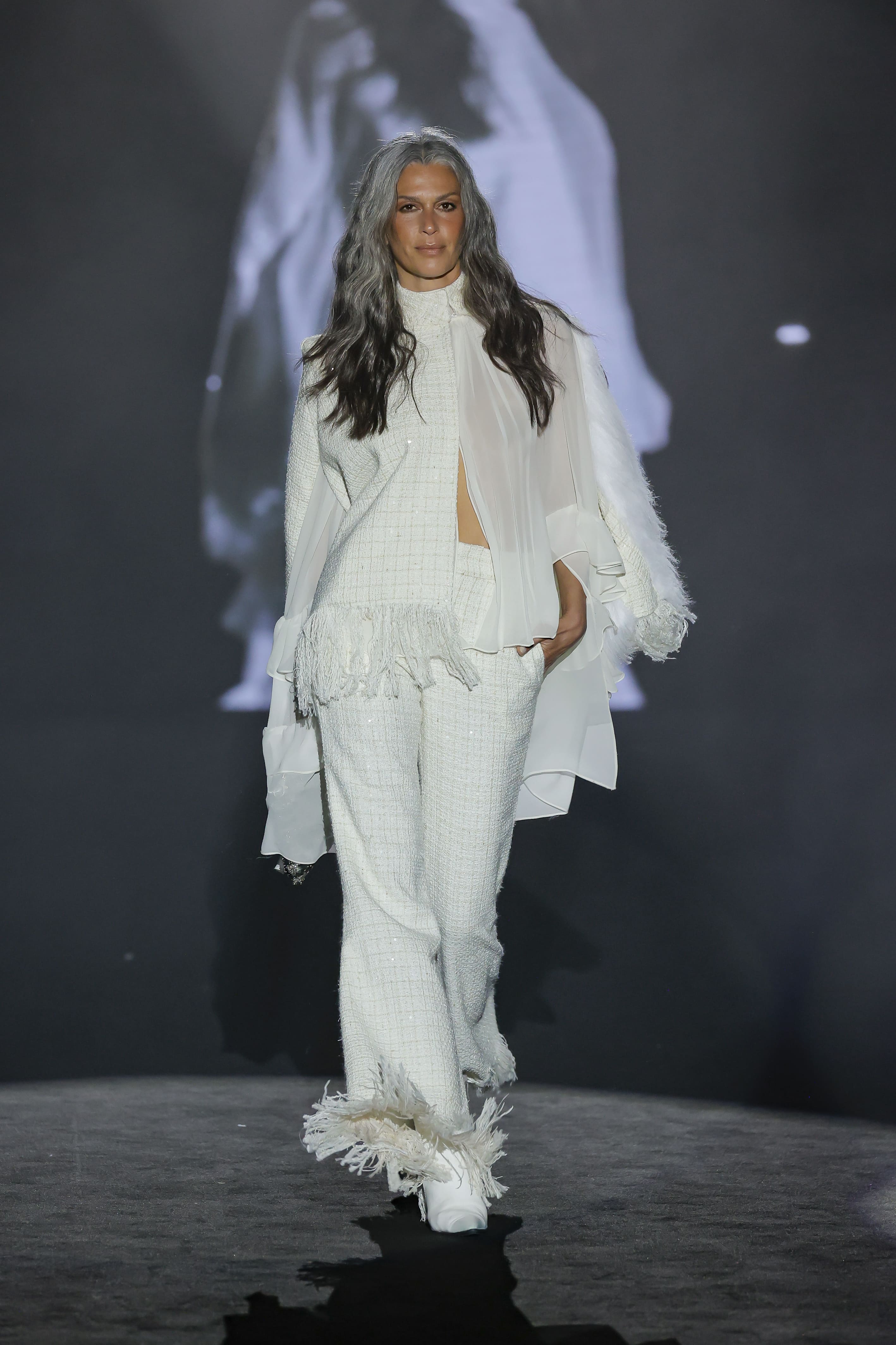 exudes serene, timeless elegance with an aesthetic that fuses classic and avant-garde. The all-white ensemble is composed of straight-cut trousers and a structured jacket.
