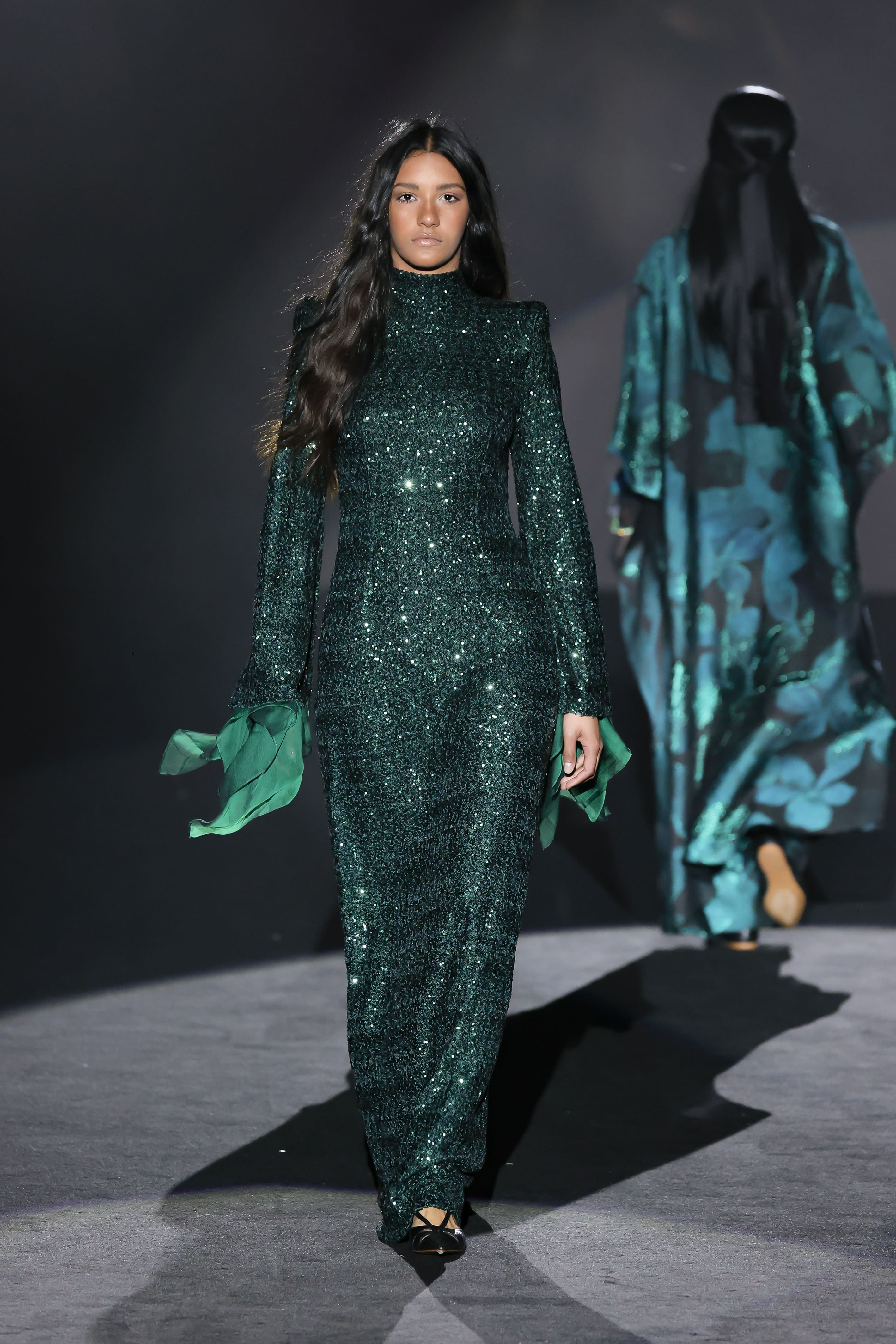 Model walks the runway in a long, bright green dress.