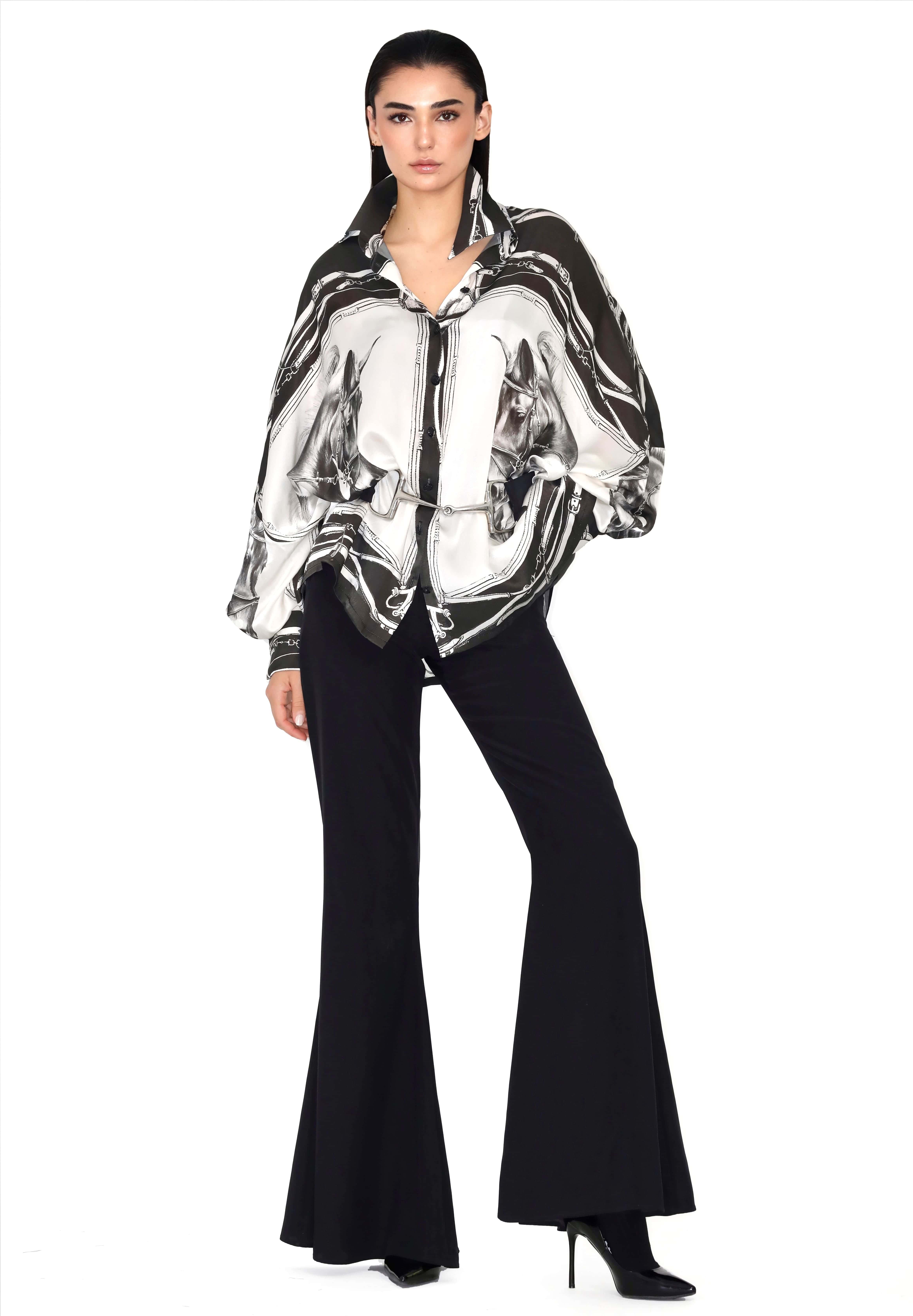 Camisa oversize de satén con estampado ecuestre en blanco y negro, combinada con pantalones negros de campana y botines de tacón