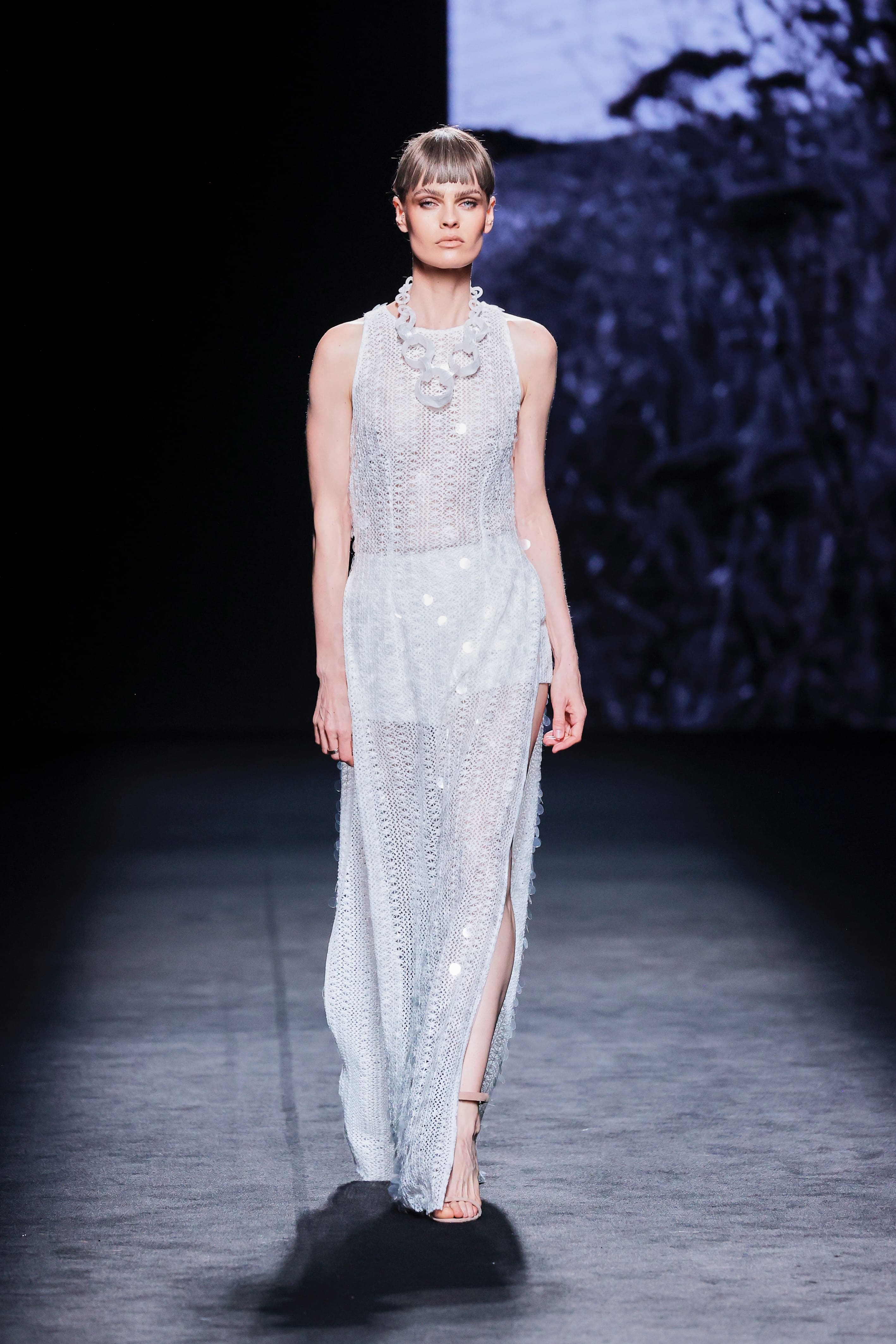 Modelo en la pasarela con vestido largo blanco semitransparente de Malne