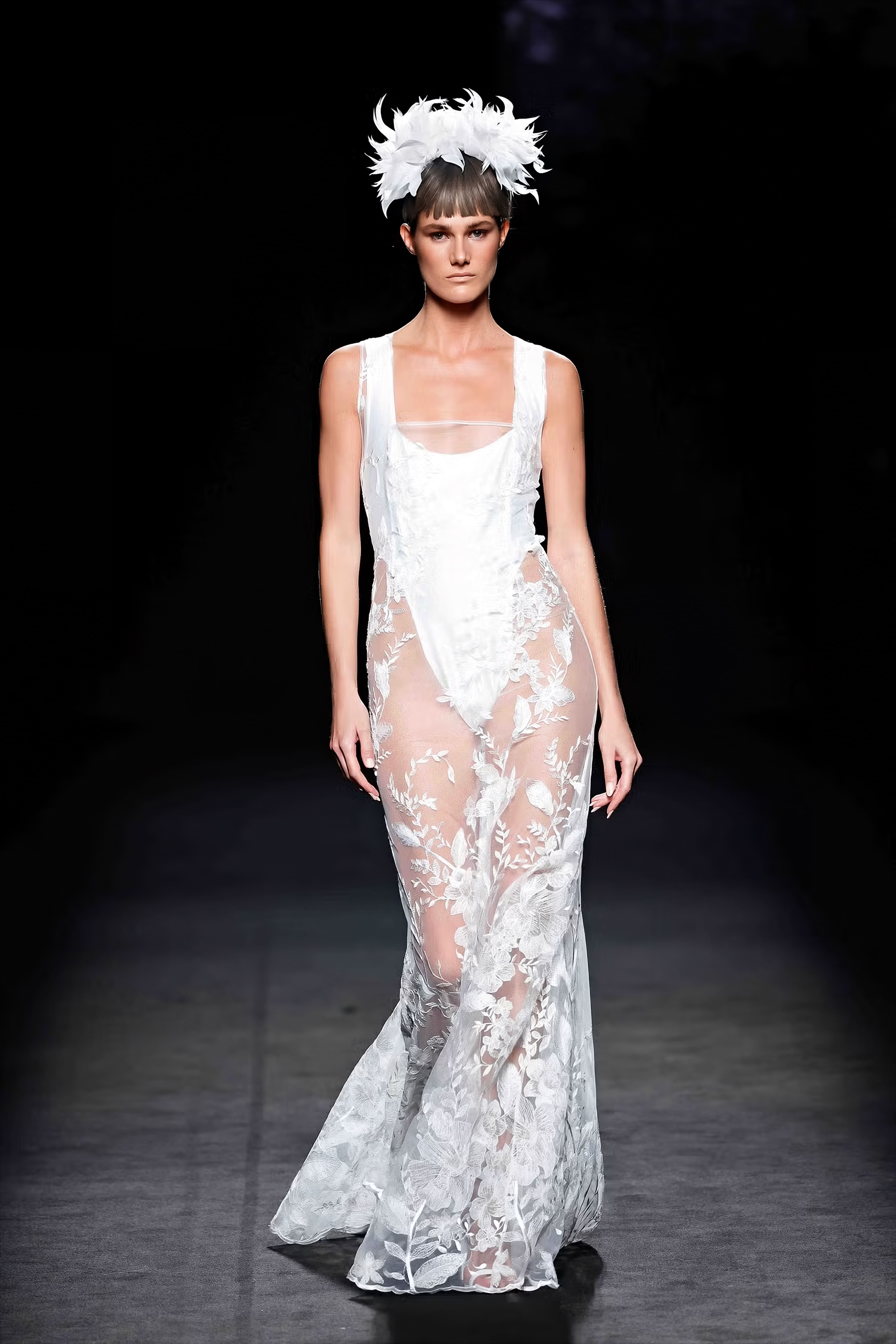 Modelo en la pasarela con vestido blanco semitransparente de Malne con bordados florales y panel central opaco.