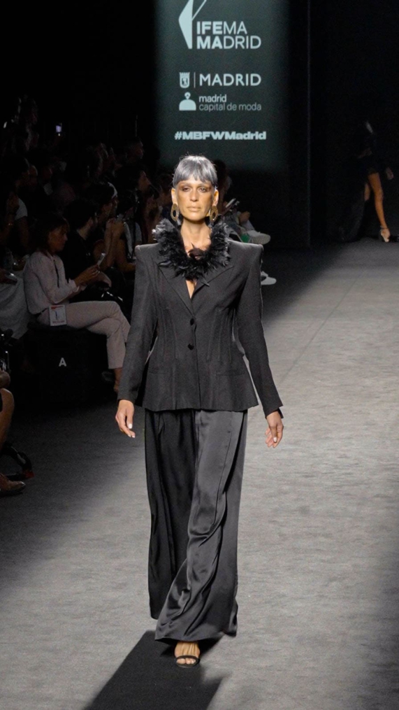 Modelo de Malne en pasarela con traje negro y detalle de plumas al cuello.