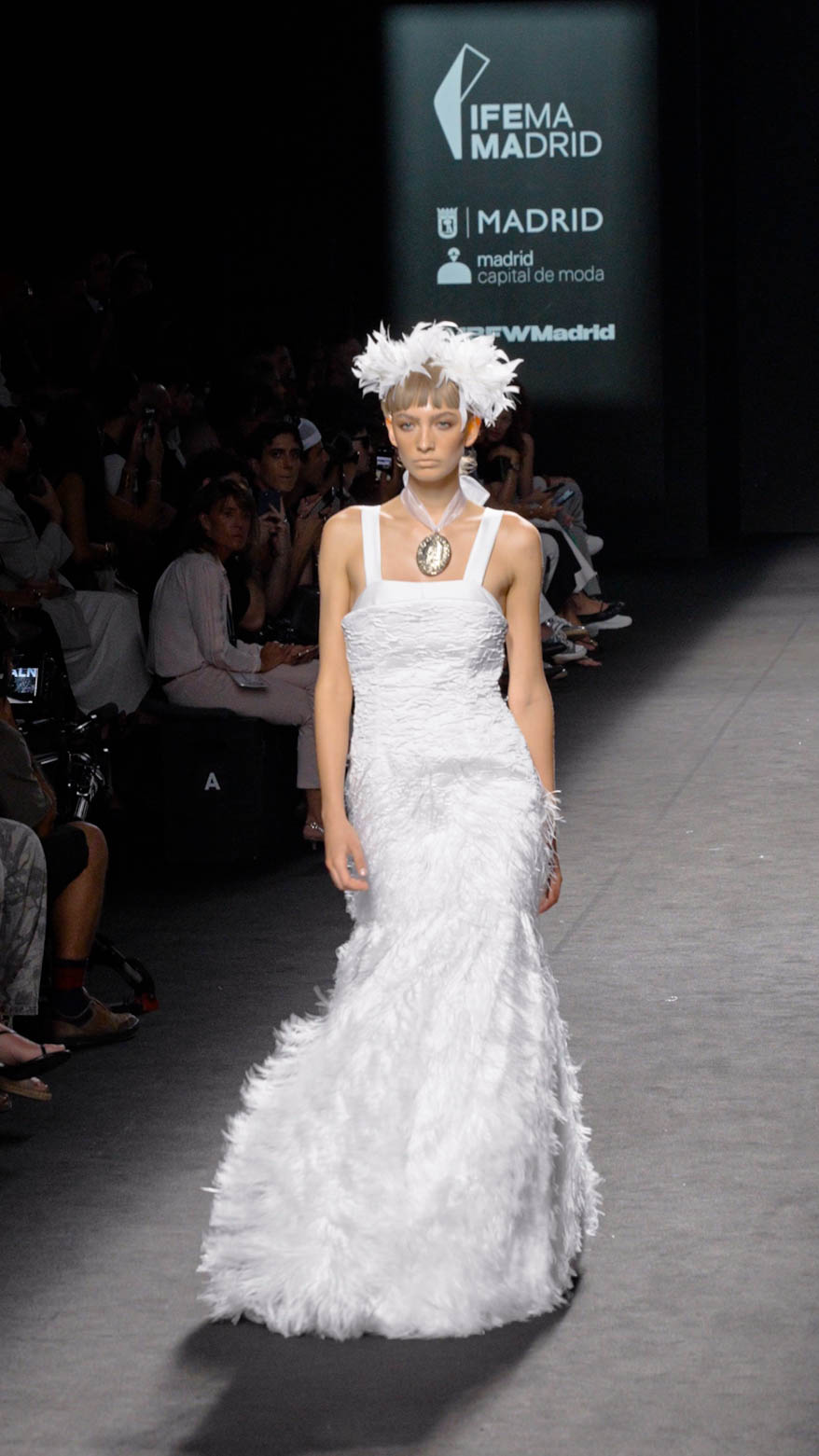 Modelo caminando por la pasarela de MBFW Madrid en IFEMA Madrid con un vestido largo blanco de tirantes finos.
