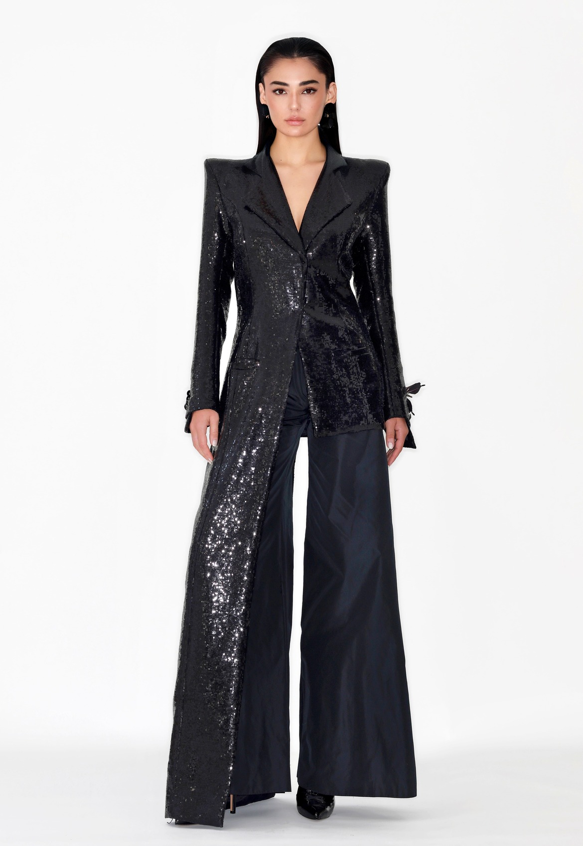 Conjunto negro de Malne con chaqueta larga de lentejuelas y hombros marcados, combinada con pantalón palazzo fluido.
