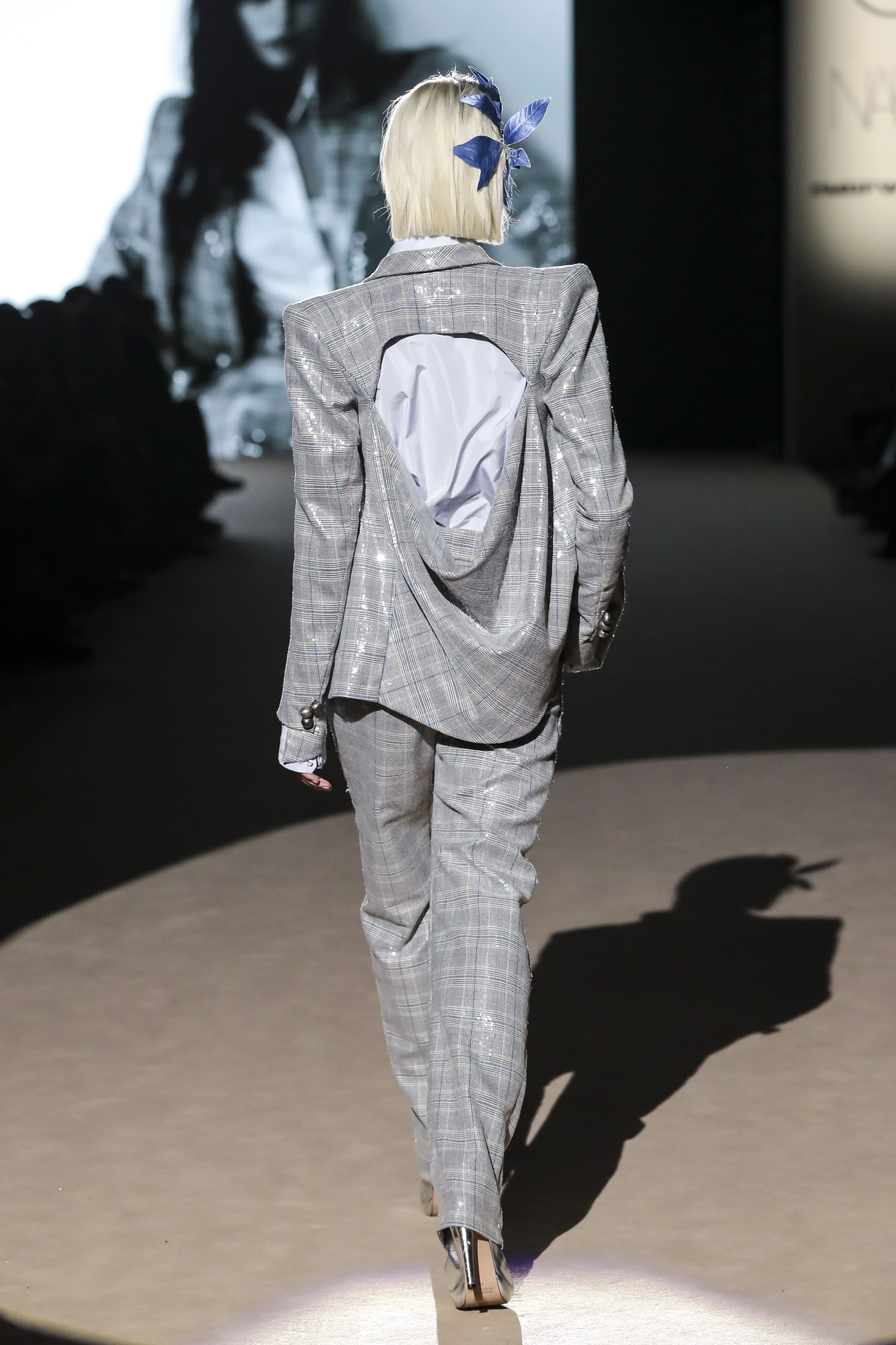 Modelo desfilando de espaldas con traje gris de cuadros de Malne en la Mercedes-Benz Fashion Week Madrid marzo de 2026 con abertura en la espalda.