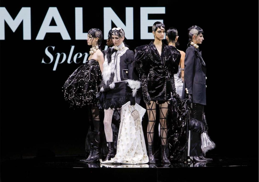 Modelos de Malne posan en pasarela con looks negros de brillo, plumas y perlas sobre fondo oscuro.